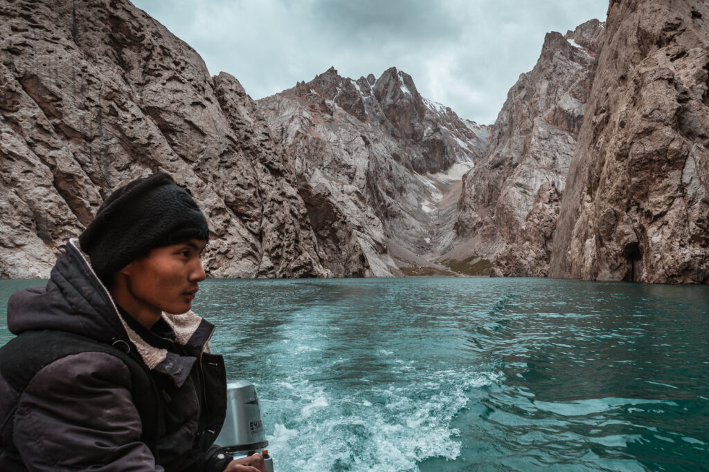 Local Kyrgyz man driving a boat in Kel-Suu Lake in Kyrgyzstan