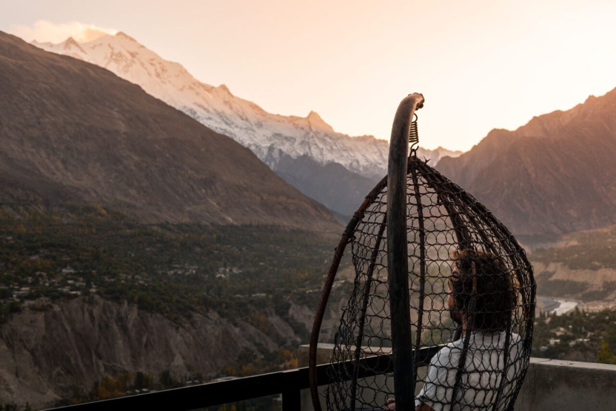 Hunza Valley: Man sitting in a chair and contemplating Rakaposhi and the valley bellow at sunset, Gilgit-Baltistan, Pakistan